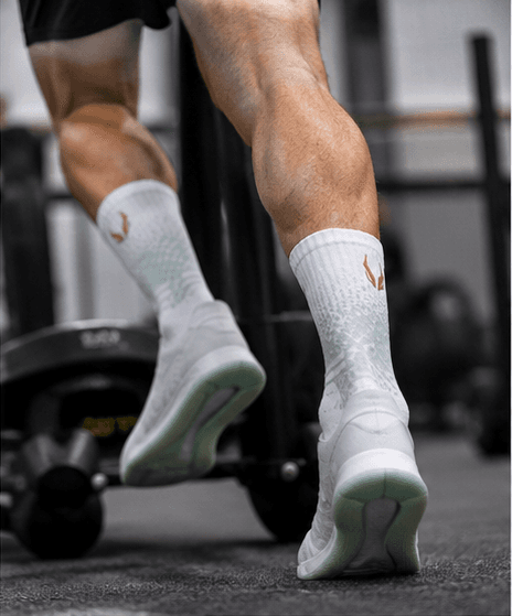 Male athlete pushing a sled during hybrid training — HOOF performance socks with gold logo visible