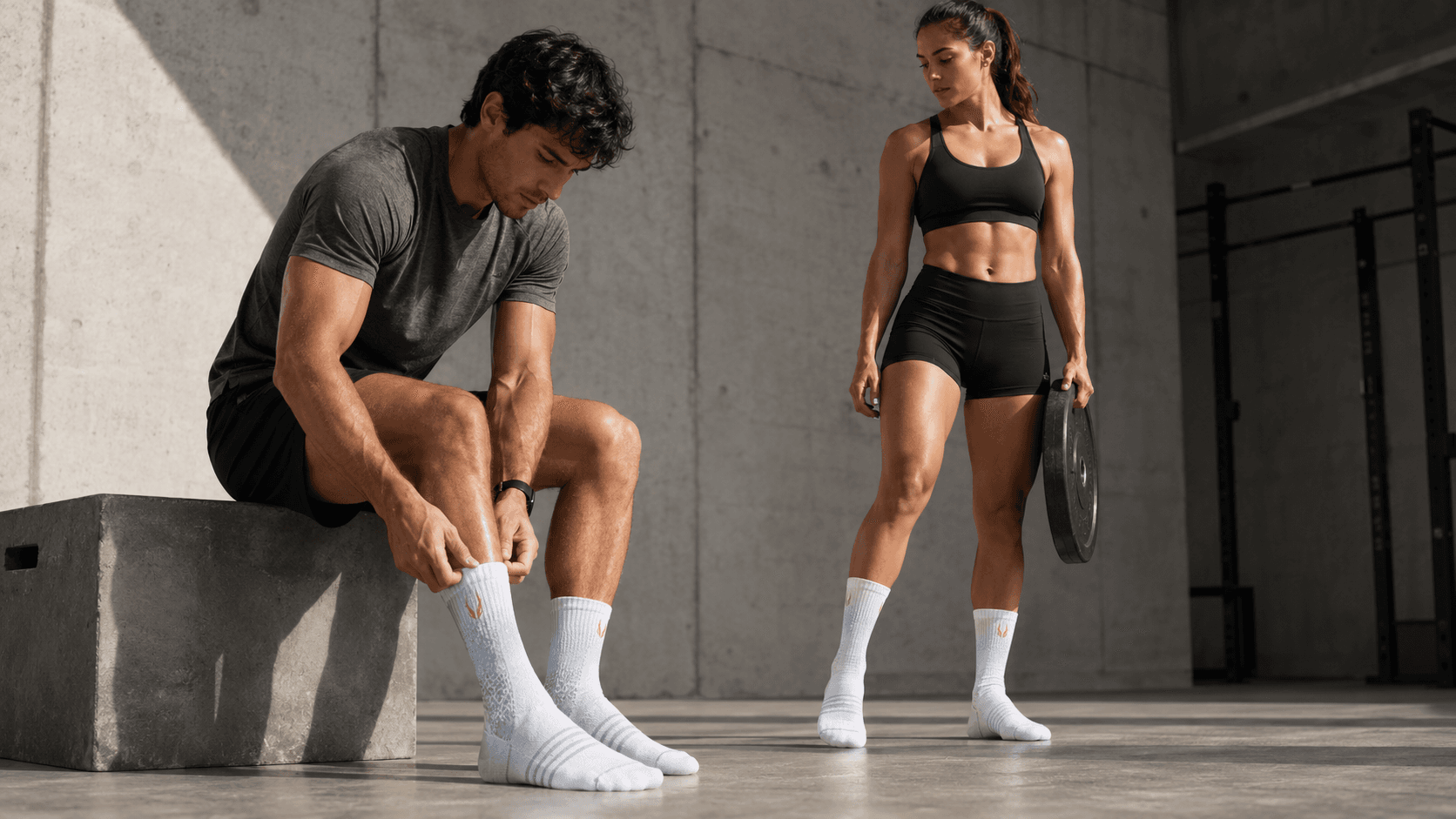 Male and female hybrid athletes wearing mid-calf HOOF performance socks in a premium concrete training space.